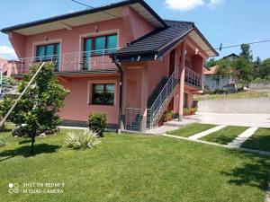une maison rose avec une pelouse devant elle dans l'établissement Guest House Ahmo Halilcevic, à Dubrave Gornje