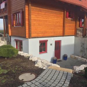 ein Haus mit roten Fenstern und einer Steinzufahrt in der Unterkunft Braunkehlchen in Straubenhardt
