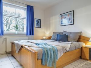 a bedroom with a bed with blue curtains and a window at Hafenstraße 38 Whg 5 in Zingst