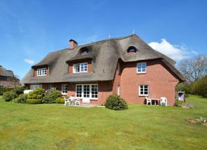 a large red brick house with a thatched roof at Bornholm Whg2 in Nieblum