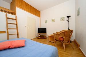 een slaapkamer met een bed, een stoel en een televisie bij Villa Christiana - Stranddistel in Graal-Müritz
