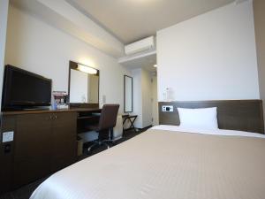 a bedroom with a bed and a desk and a television at Hotel Route-Inn Ishinomaki Kanan Inter in Ishinomaki