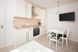 a kitchen with white cabinets and a table and chairs at Schleiblick App 11 in Rabenkirchen-Faulück