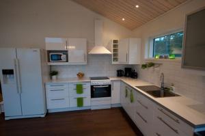 cocina con armarios blancos y nevera blanca en Svinö Waterfront Villa, en Lumparland