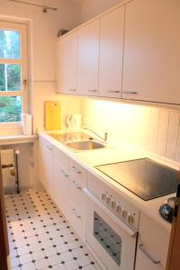 a kitchen with white cabinets and a sink at Finke-Ferienhaus - EG in Grömitz
