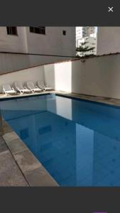 a swimming pool with lounge chairs next to a building at Guaruja ap lindo 200 m da praia in Guarujá