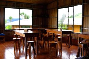 un restaurante con mesas y sillas de madera y ventanas en Casitas de Montaña Cabuya en Monteverde