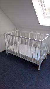- un lit bébé blanc dans une chambre avec fenêtre dans l'établissement Haus Linden, à Hage