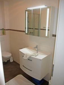 a white bathroom with a sink and a mirror at "Landhaus Voss" Typ 4 Nr12 in Staberdorf
