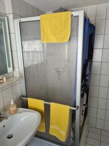 ein Bad mit einer Dusche, einem Waschbecken und gelben Handtüchern in der Unterkunft Haus Lauterberg 1 - Das Urlaubsdomizil im Harz in Bad Lauterberg