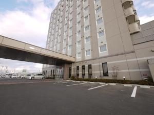 a parking lot in front of a large building at Hotel Route-Inn Ishinomaki Kanan Inter in Ishinomaki