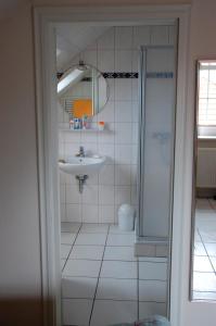 a white bathroom with a sink and a shower at Privatzimmer Ehrhardt Nr1 in Burg auf Fehmarn