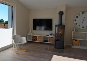 ein Wohnzimmer mit einem TV, einem Stuhl und einer Uhr in der Unterkunft Langeland in Kronsgaard