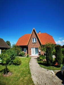 ein Haus mit rotem Dach und einem Backsteinsteg in der Unterkunft Am Norderfeld 17 in Großenbrode