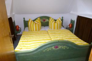 um quarto com uma cama verde e amarela com almofadas em Heublein em Poseritz