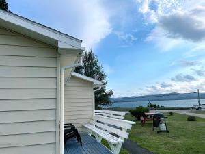 two white benches sitting on the side of a house at Sea Breeze Cottages in Ingonish