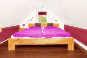 uma cama de madeira com lençóis roxos num sótão em Haus Sonnenschein em Dänschendorf