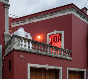 a red building with a balcony with a clock on it at Casa Nada Hotel in Guanajuato