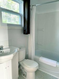 a white bathroom with a toilet and a sink at Sea Breeze Motel in Ingonish