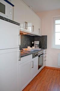 a kitchen with white appliances and a wooden floor at "Landhaus Voss" Typ 2 Nr5 in Staberdorf