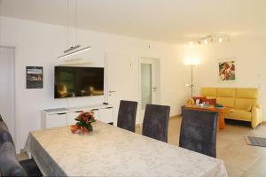 a dining room with a table with chairs and a television at Haus Waldwiese in Fuhlendorf