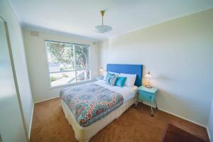 a bedroom with a bed with a blue headboard and a window at 150 Steps FREE WI-FI in Apollo Bay