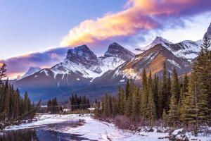 a snowy mountain range with a river and trees at Banff Gate vacation townhouse in Canmore