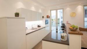 cocina con armarios blancos y encimera en SPA Apartment FIRST Sellin, en Ostseebad Sellin