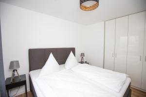 1 dormitorio con cama blanca y almohadas blancas en Ferienwohnung PlauOase en Plau am See