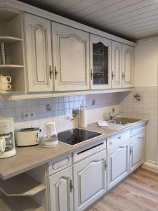una cocina con armarios blancos y fregadero en Flying Dutchman - a28400 en Schönberger Strand
