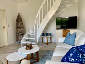 uma sala de estar com um sofá branco e uma televisão em FeWo Seegras em Grödersby