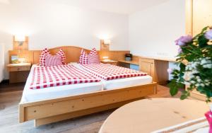 - une chambre avec un lit en bois et des oreillers rouges et blancs dans l'établissement Hirschberg, à Bad Wiessee