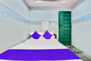 a bedroom with a large bed with purple pillows at SPOT ON Gayatri Comforts in Bengaluru +40 photos