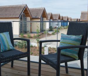 two chairs on a deck with a house in the background at Ostsee - Appartement Nr 87a "Strandkorb" im Strand Resort in Heiligenhafen