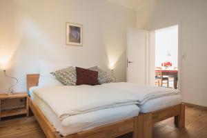 um quarto com uma cama grande e lençóis brancos em Oesenhof - Dielenwohnung em Bad Fallingbostel