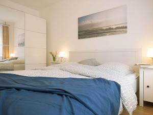 a white bedroom with a bed with blue sheets at Alte Reihe 10 - Silbermöwe 2 in Zingst