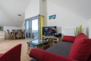 a living room with a red couch and a tv at Ostsee - Appartement Nr 26 "Piratennest" im Strand Resort in Heiligenhafen