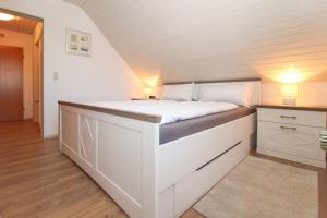 um quarto com uma cama branca num quarto em Muckelstuuv in Greetsiel em Greetsiel