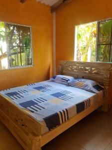 Cama de madera en habitación con 2 ventanas en Cabaña cerca al mar - A 200 mts, en Coveñas