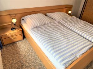 a bed with a blue and white striped comforter at Haus Uschi - Ferienhaus in Cismar