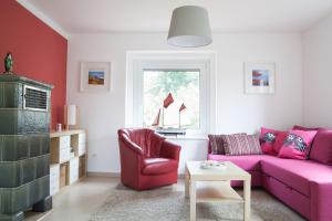 a living room with a pink couch and a chair at Carpe Diem Dahme in Dahme