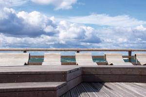 ハイリゲンハーフェンにあるOstsee - Reetdachhaus Nr 3 "Südstrand Lodge Marina-Bay" im Strand Resortの海を見渡すウッドデッキに座る椅子