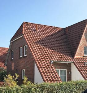 ein Haus mit rotem Dach mit in der Unterkunft Dat Onnens Hus - Burhave 03 in Butjadingen