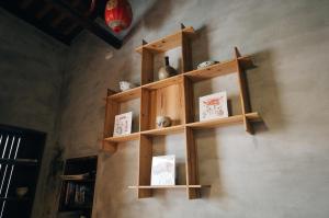 a wooden shelf on a wall with books at Kinba Guest House in Jinning