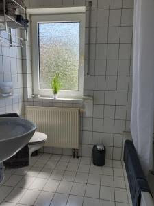 a bathroom with a sink and a toilet and a window at Ferienwohnung Bernhard in Germersheim