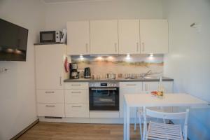 a kitchen with white cabinets and a white table at Scheune 9 in Gollendorf