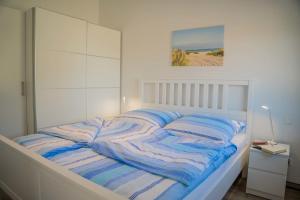 a white bedroom with a bed with striped blankets at Scheune 9 in Gollendorf
