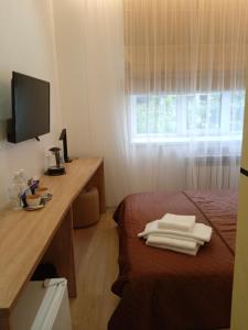a room with a bed with a desk and a television at EP Boutique Hotel Askold in Vladivostok