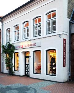 een winkel voor een wit gebouw met ramen bij Kunst&Handwerk in Eckernförde