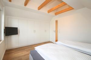1 dormitorio blanco con 1 cama y TV de pantalla plana en Ferienhaus "Auf hoher See", en Südbrookmerland